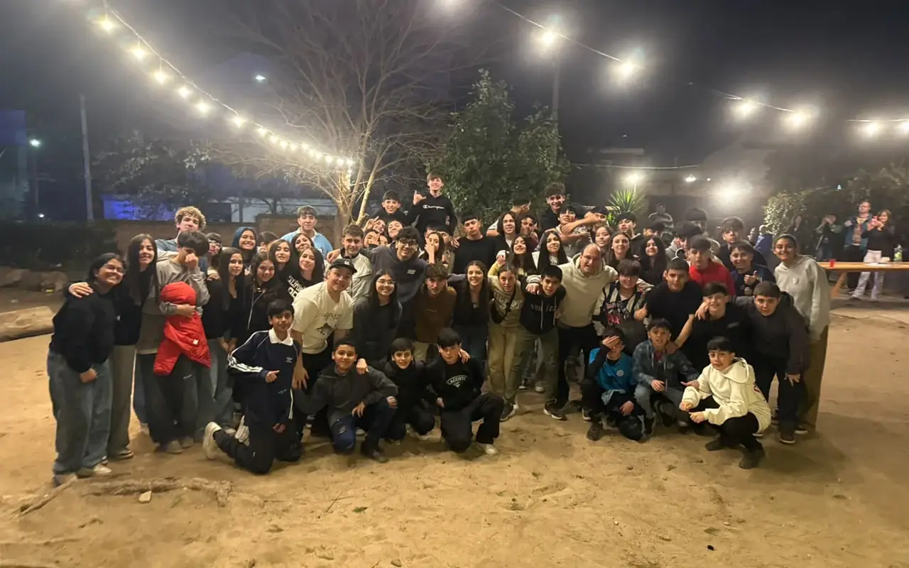 Jóvenes de La Juntada reunidos de noche en el patio de la parroquia, bajo las guirnaldas de luces